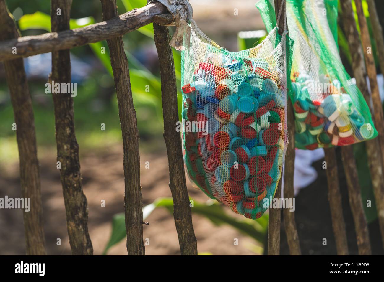 A lot of plastic bottle caps collected in a bag. Garbage that pollute the Earth. Stock Photo
