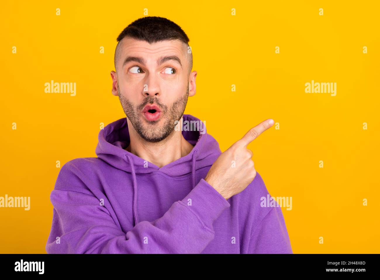 Photo portrait young man wearing purple hoody curious pointing copyspace isolated vibrant yellow color background Stock Photo