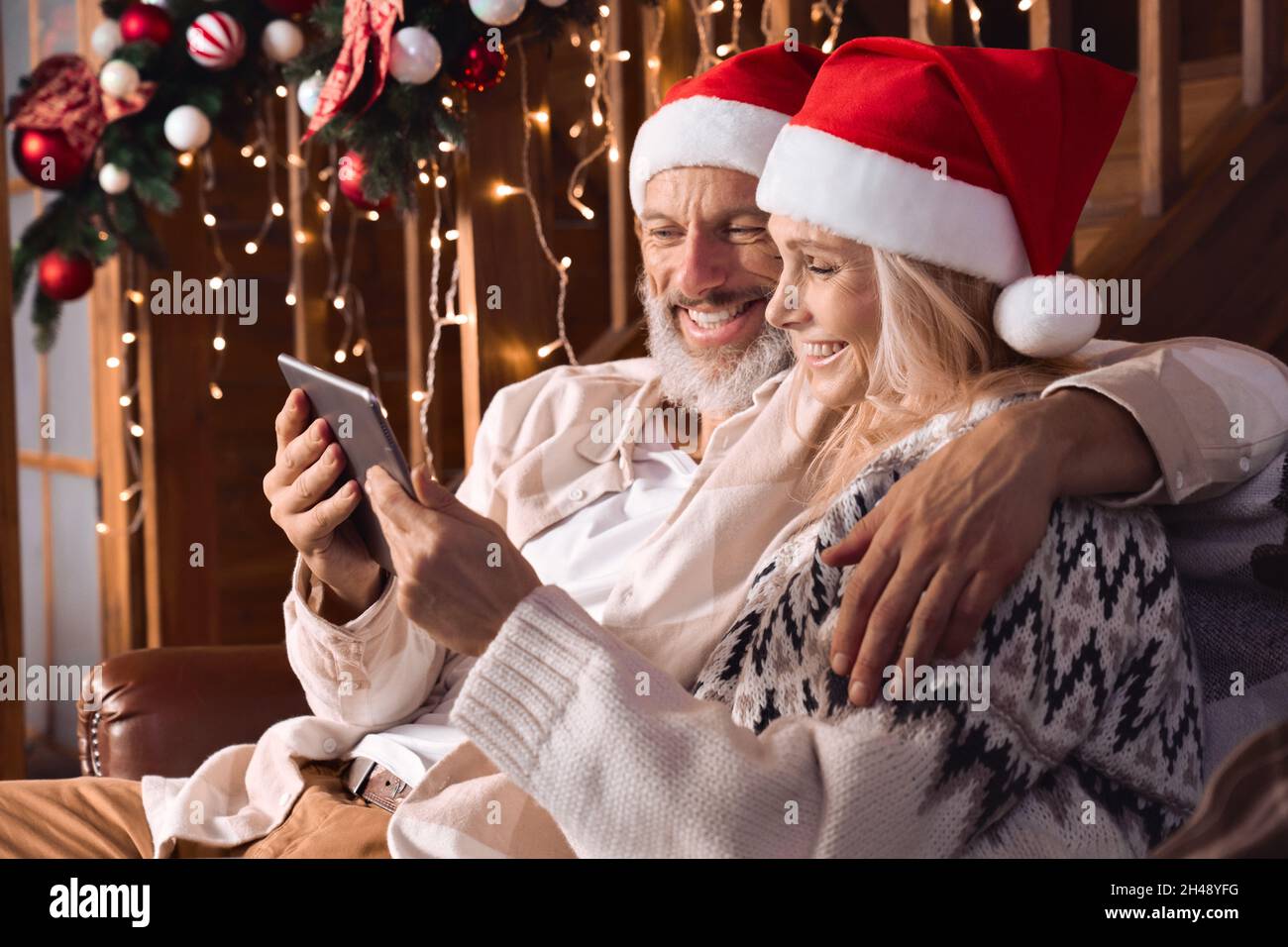 Happy grandparents old couple greeting family on Christmas video call. Stock Photo
