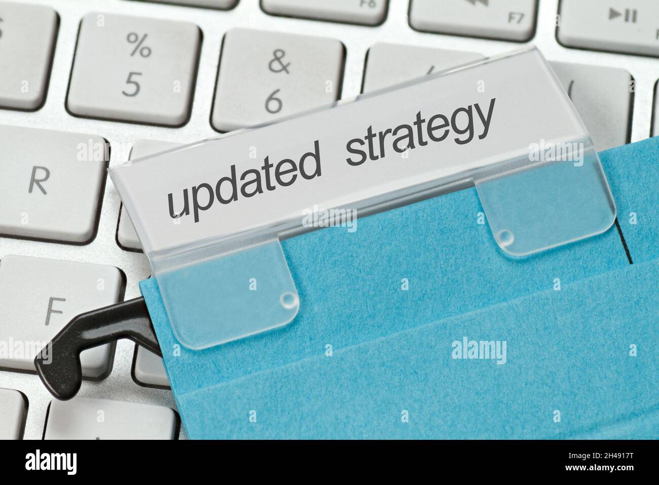 blue hanging file with the term updated strategy on a computer keyboard Stock Photo