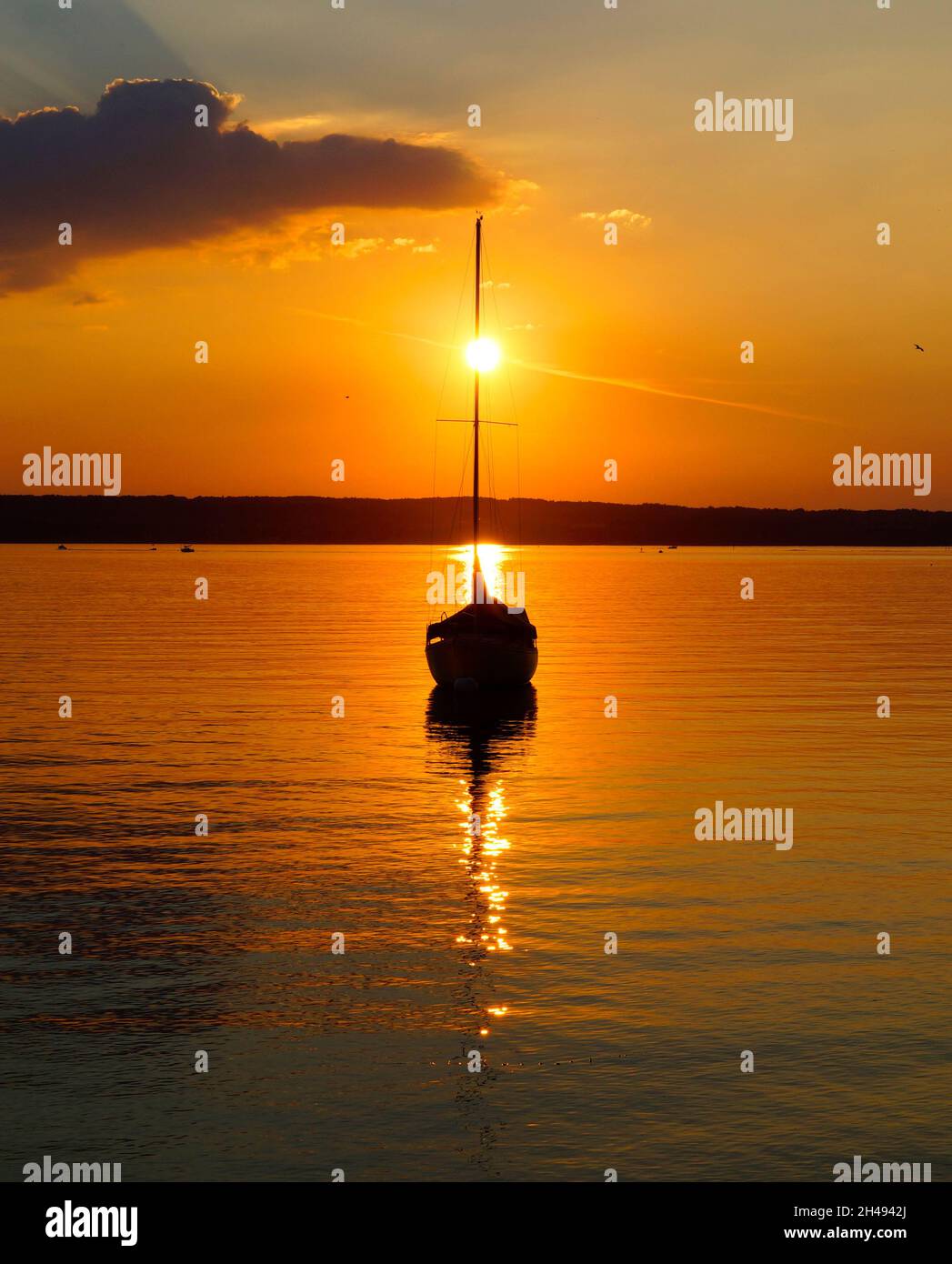 sunset at lake Ammersee in Herrsching with a sailing boat resting on the water on a warm August night (Bavaria, Germany) Stock Photo