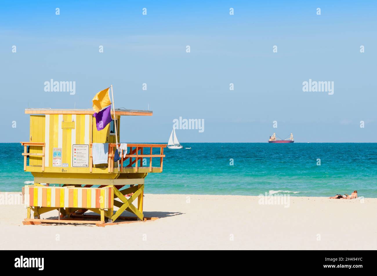 Panoramic view of Miami Beach with a wooden lifeguard station with warning flags. In the background boats sailing Stock Photo