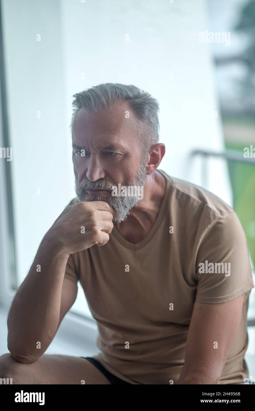 Pensive man sitting alone in a room Stock Photo
