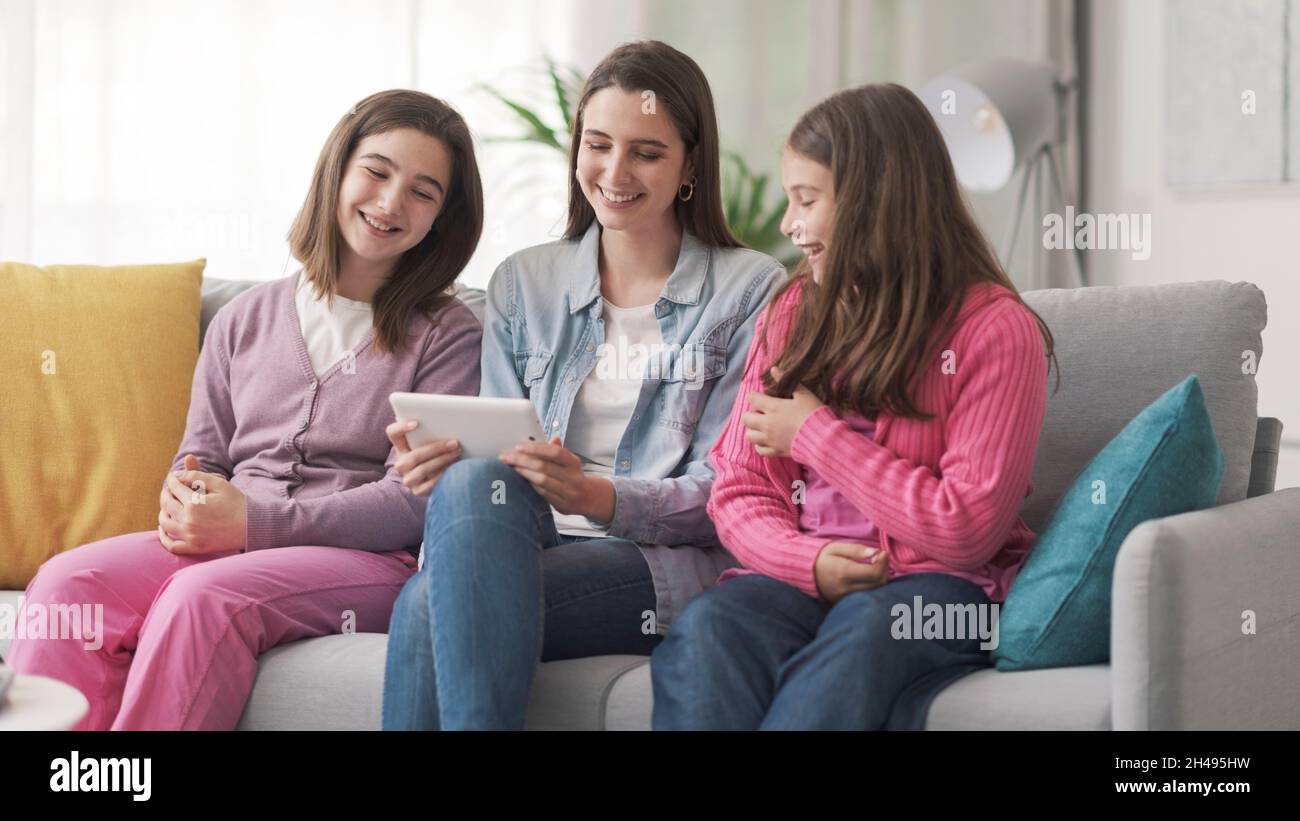 Happy girls sitting on the sofa and connecting with a digital tablet ...