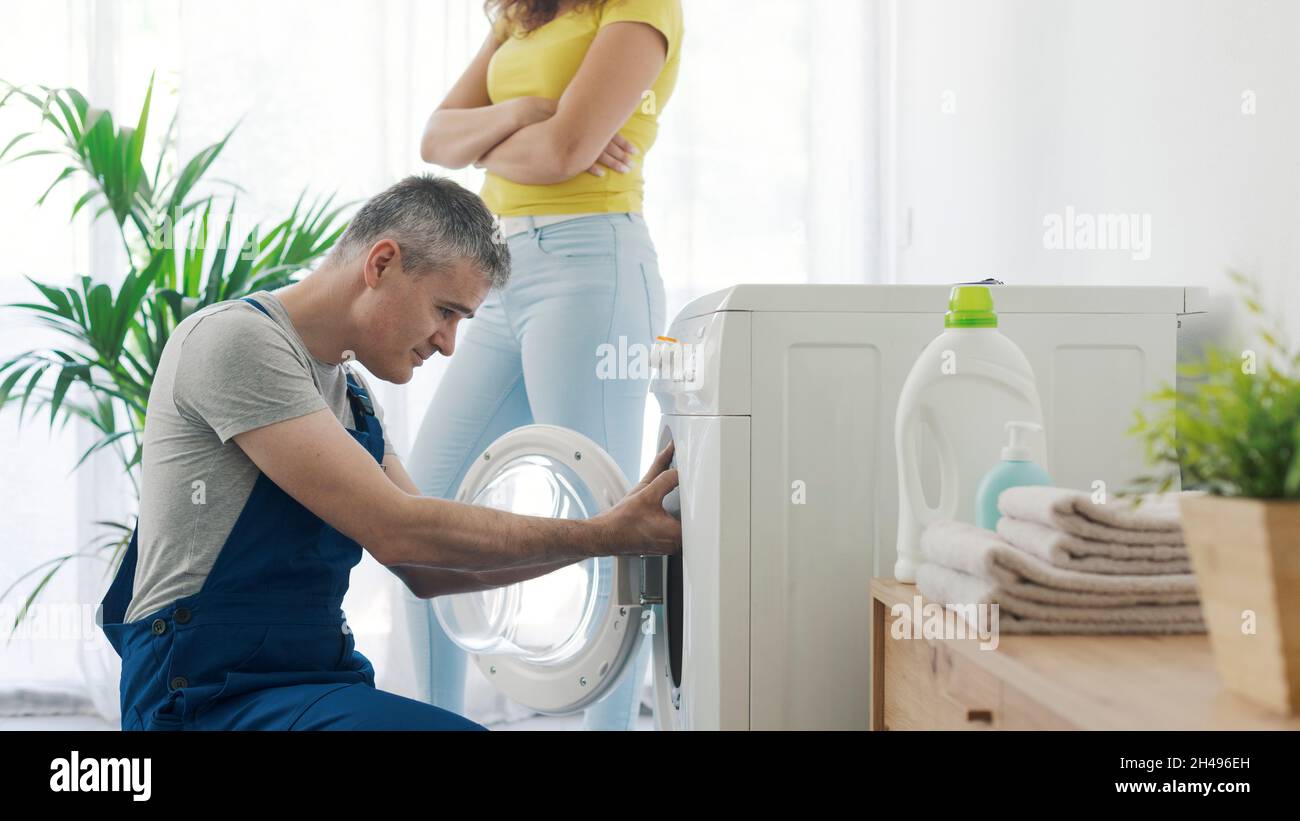 Repairman checking a broken washer, the customer is standing next to
