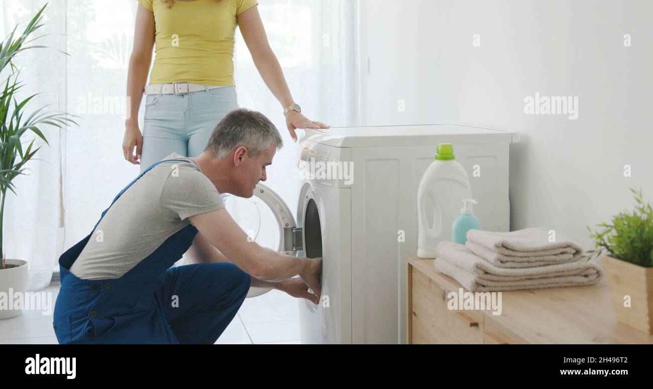 Technician repairing a washing machine at home, he is checking the gasket Stock Photo