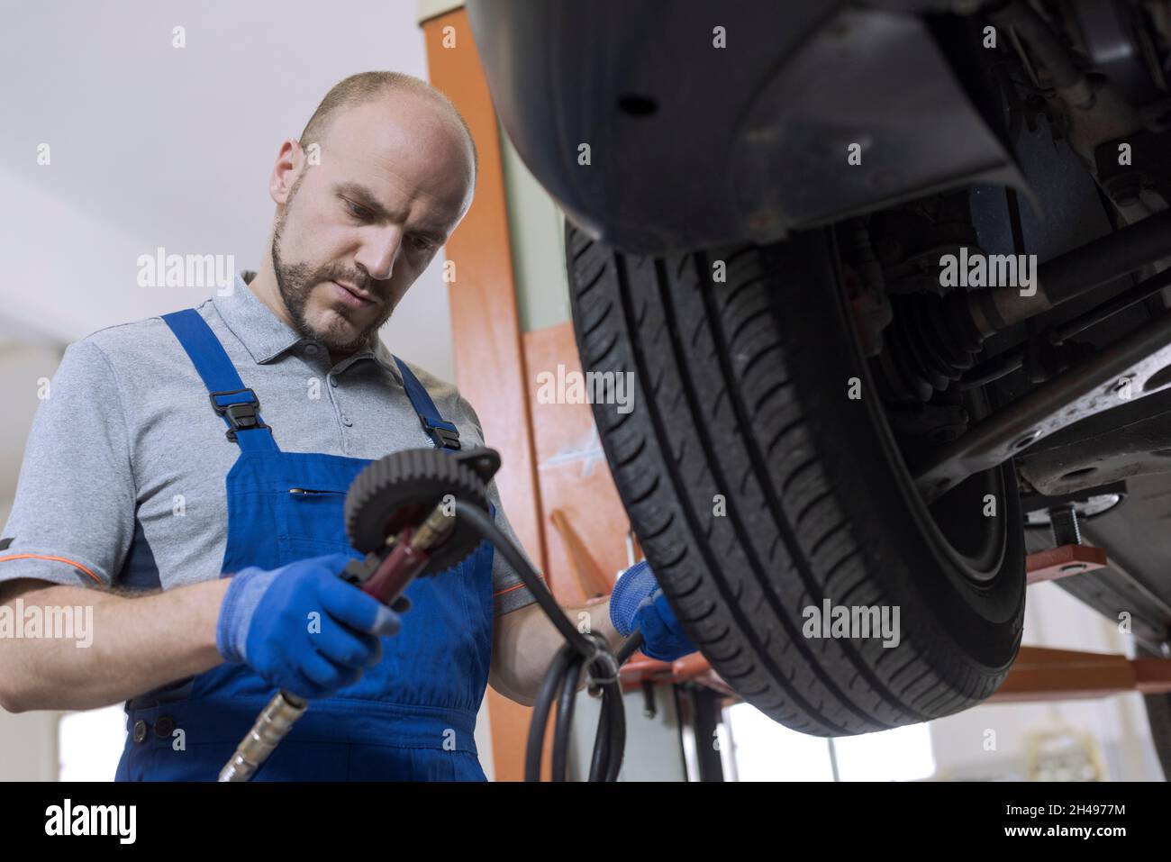 Mechanic inflating a tire and checking air pressure with a pressure