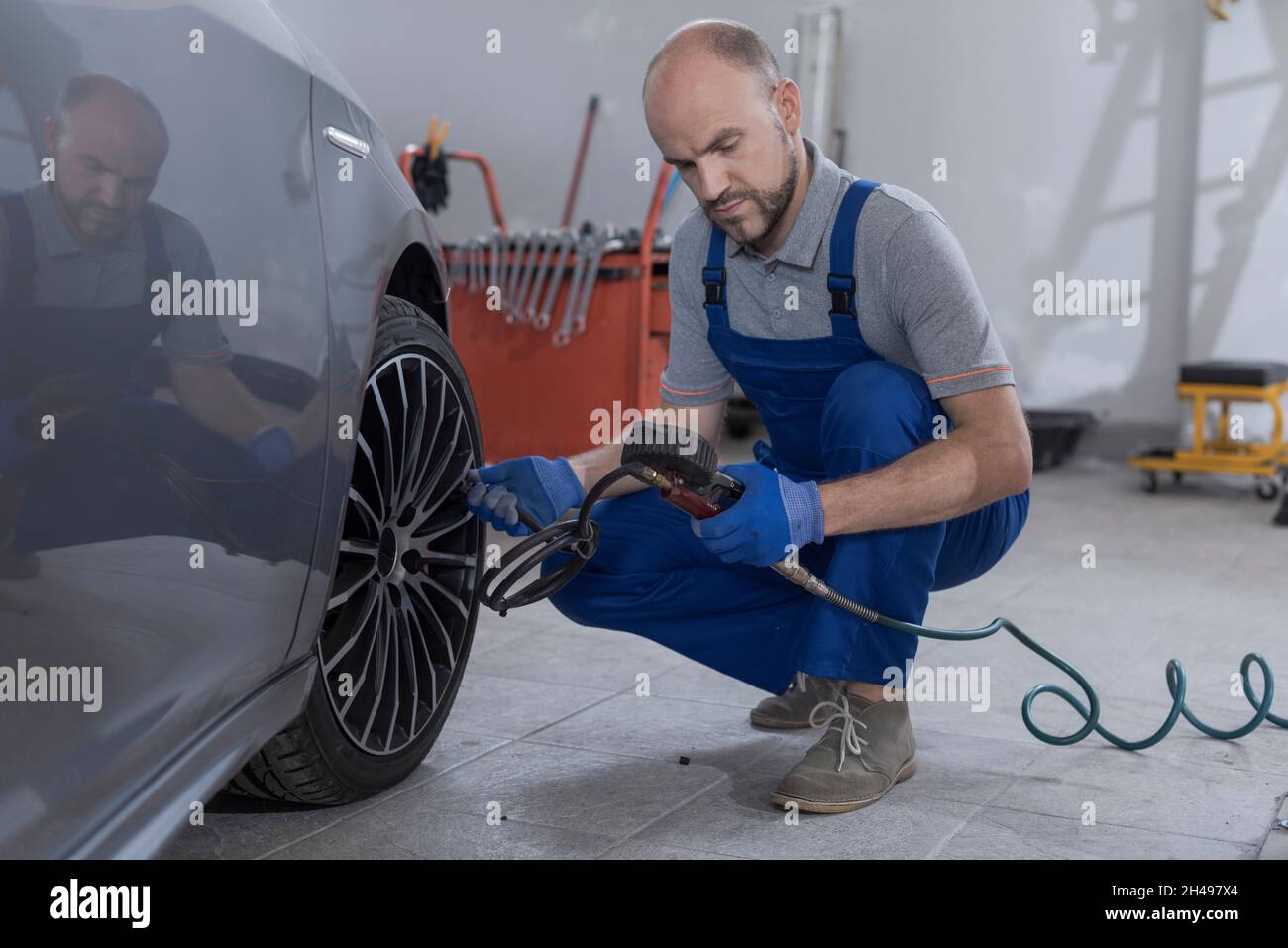 Mechanic inflating a tire and checking air pressure with a pressure