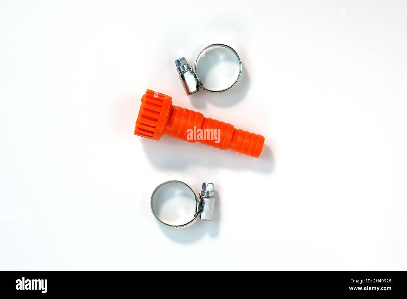 Fitting connector and metal clamp on a white background top view. Plastic orange fitting for a garden hose. Plastic hose connector and galvanized stee Stock Photo