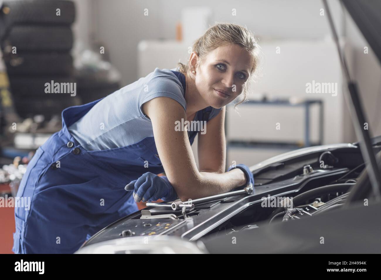 Female mechanic working at the auto repair shop, she is checking a