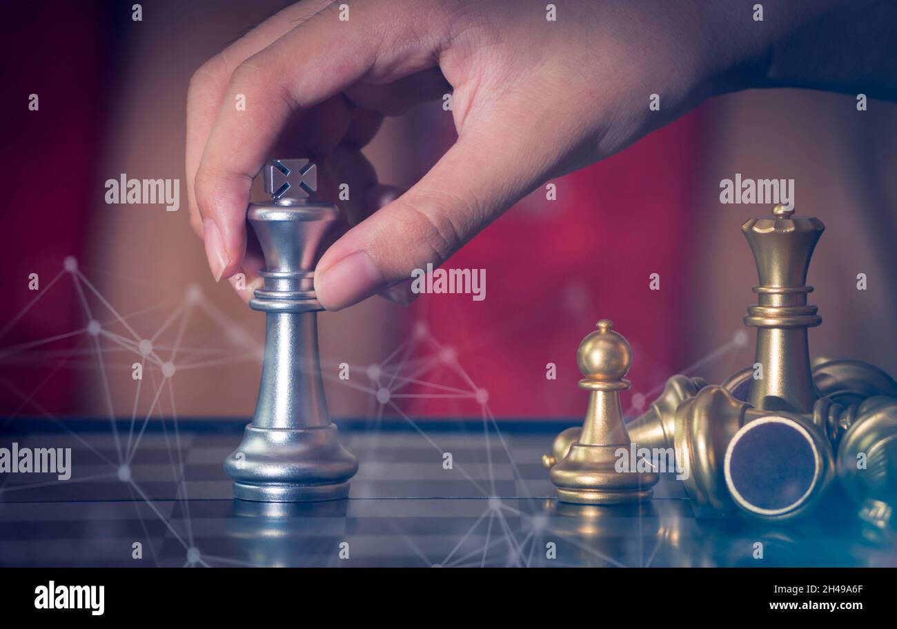 Hand businessman moving the golden knight chess fighting silver knight with fire sparks chess on chess board to successfully in the competition. Manag Stock Photo