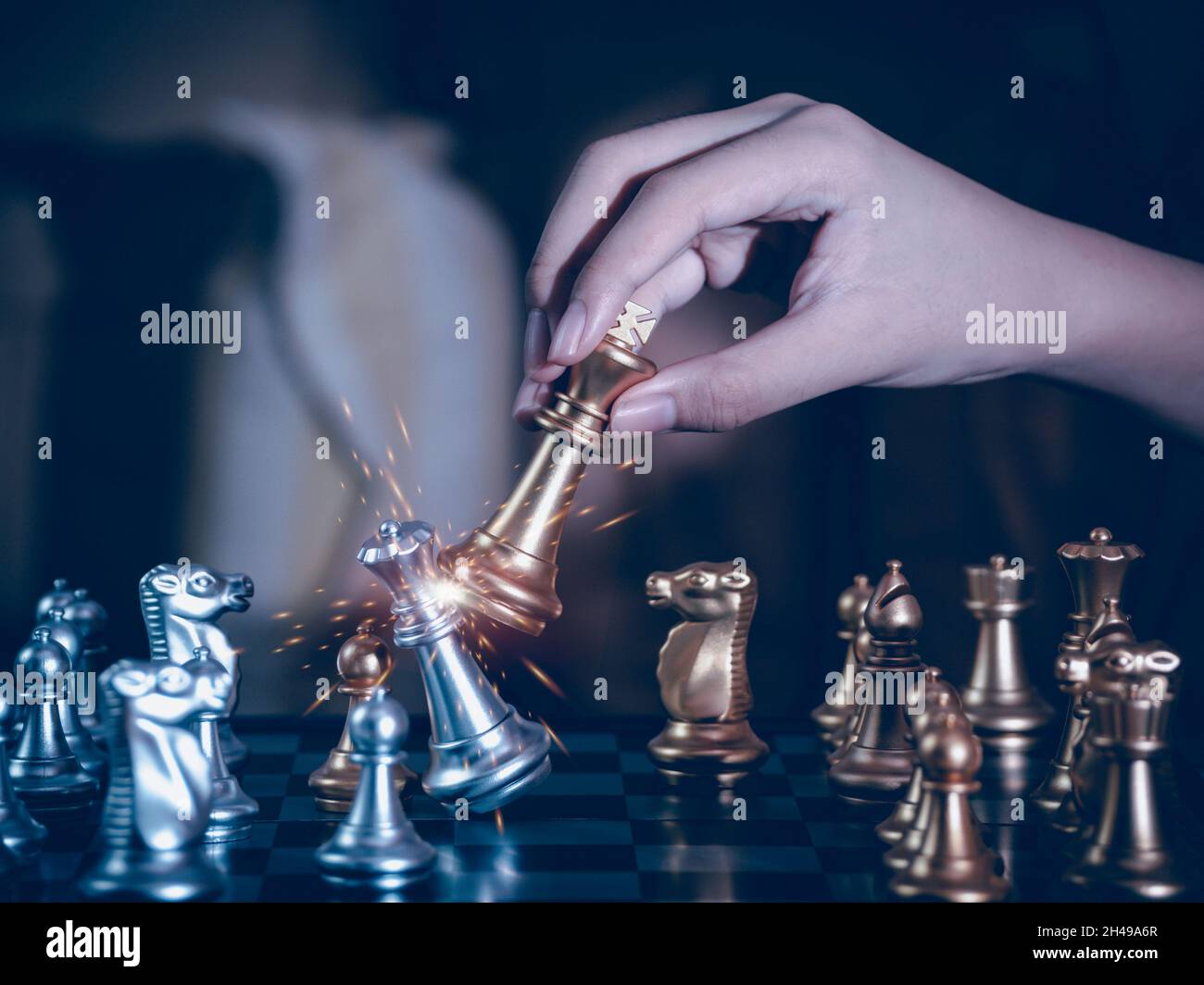 Hand businessman moving the golden knight chess fighting silver knight with fire sparks chess on chess board to successfully in the competition. Manag Stock Photo