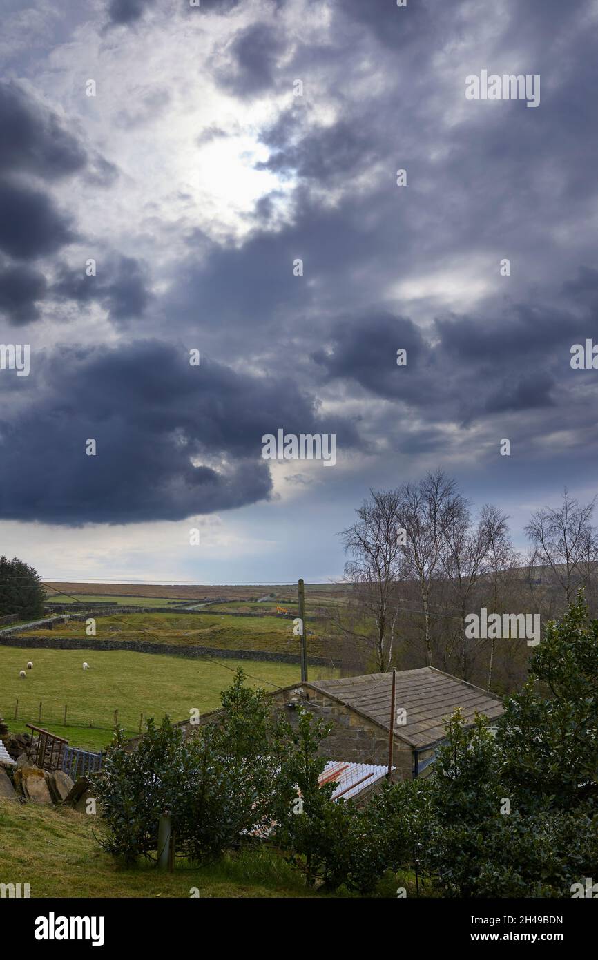 April and stormy skies over Yorkshire moorland and smallholding barn Stock Photo