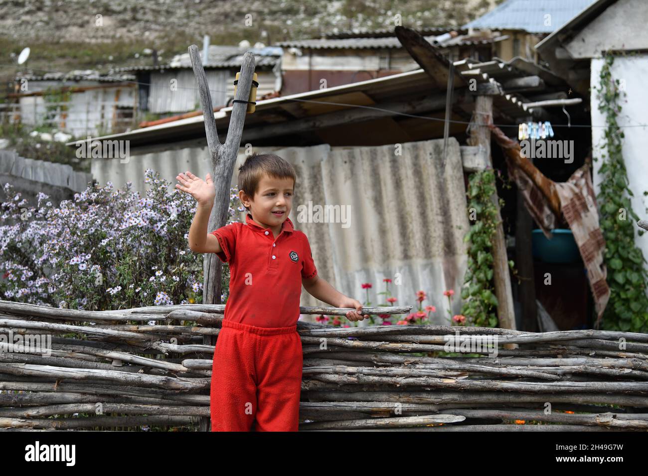 Chechnya, Russia - Sept 12, 2021: Little Chechen boy shown at his house with a welcome hand gesture Stock Photo