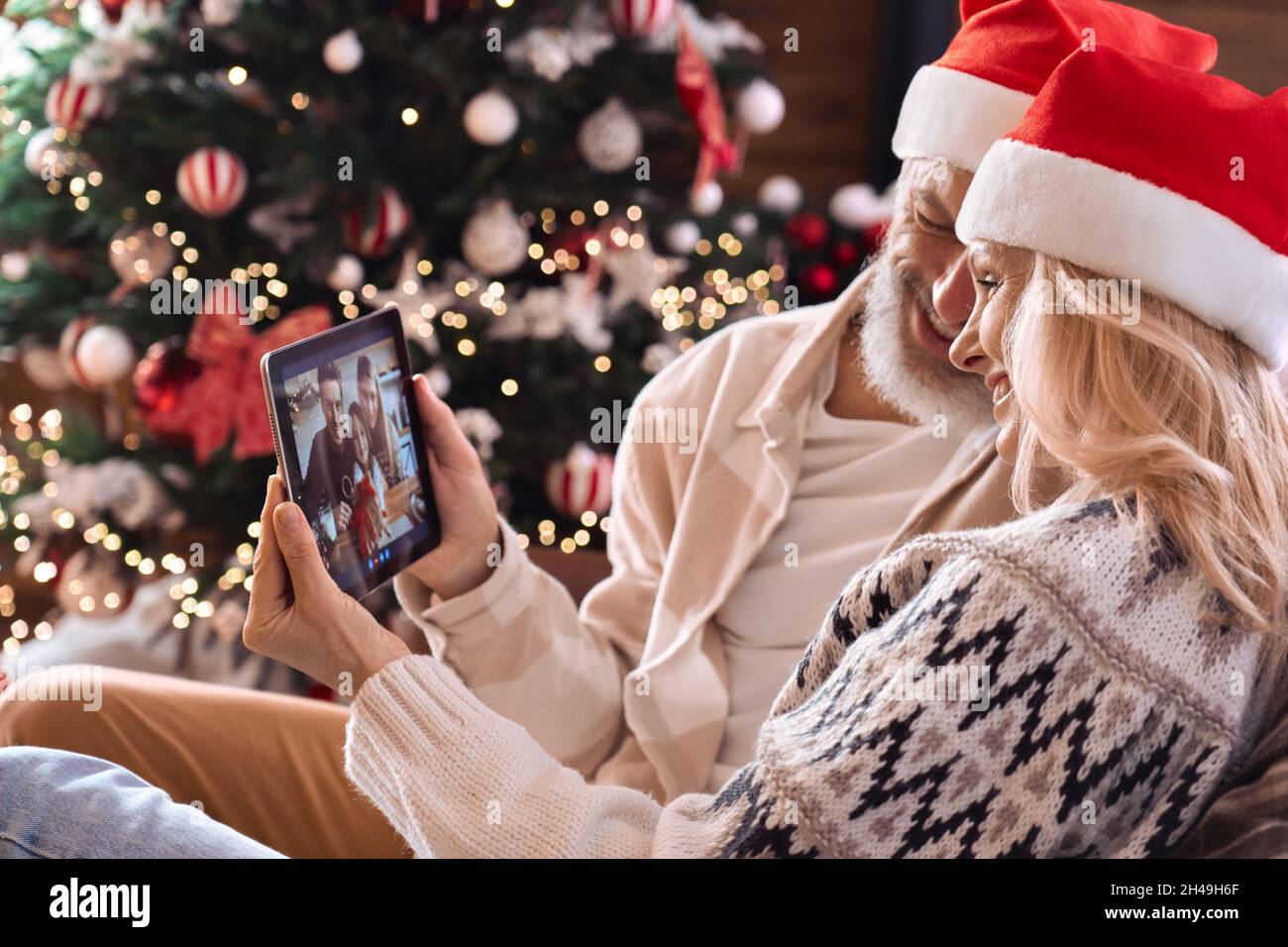 Happy grandparents couple greeting family on Christmas virtual video call. Stock Photo