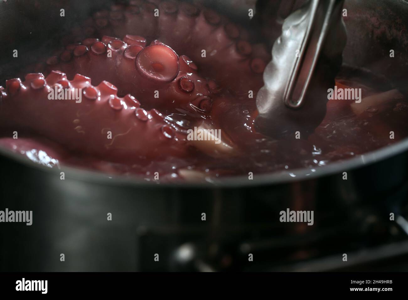 Whole octopus boiling in the the pot filled with water and vegetables ...