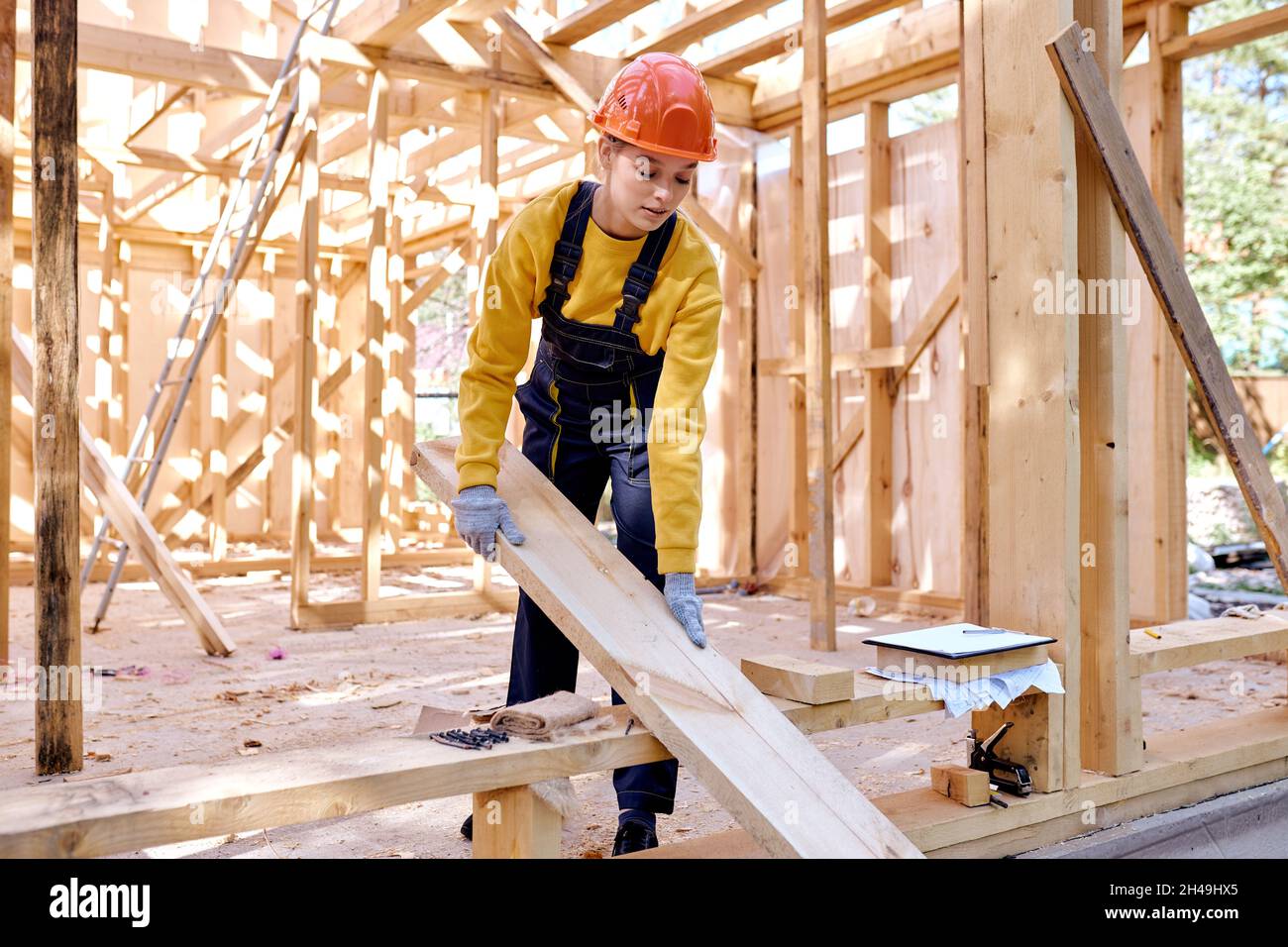 confident female constructor working on wooden construction site ...
