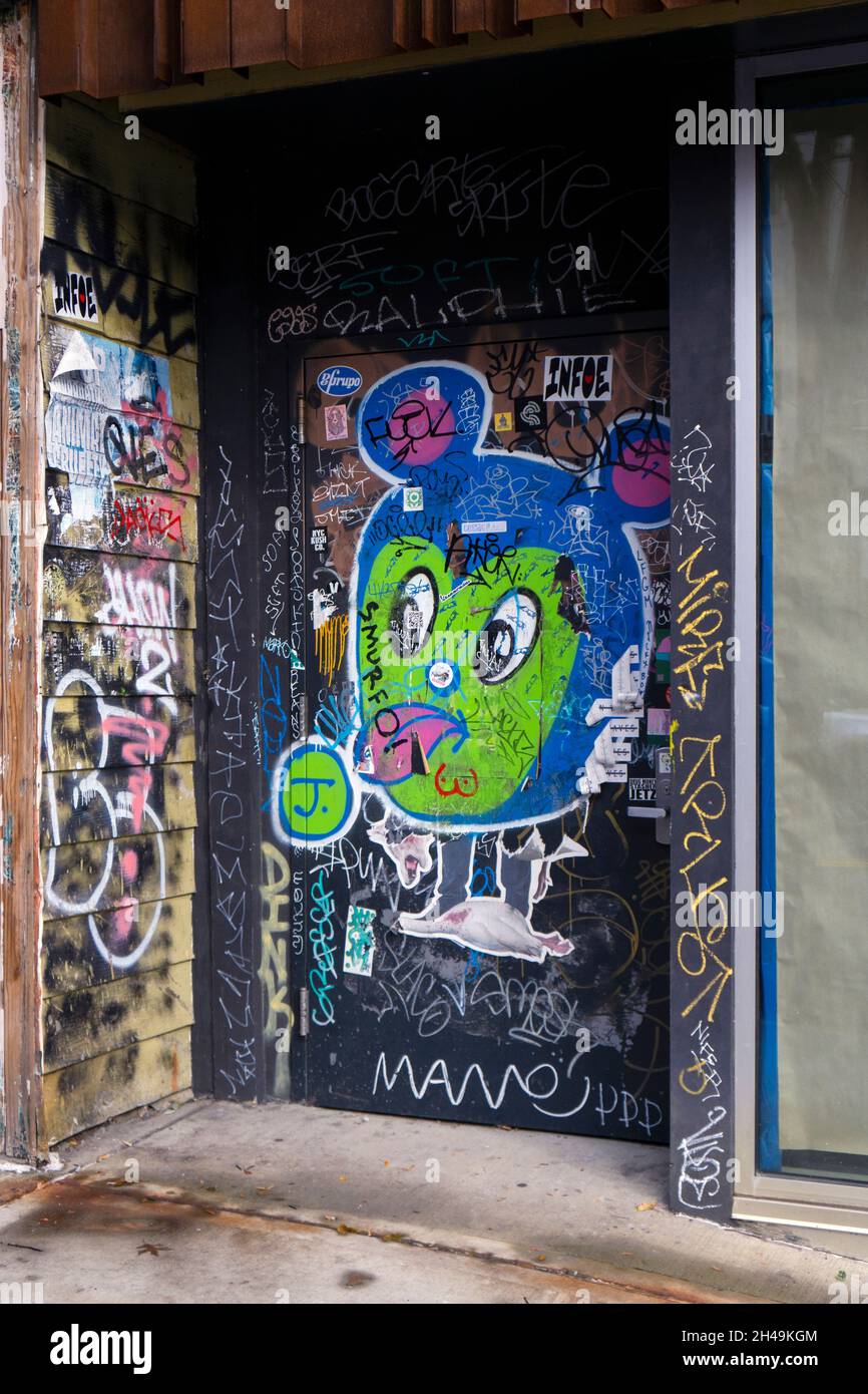 A doorway with a collage of graffiti, stickers, and tags. On Grand