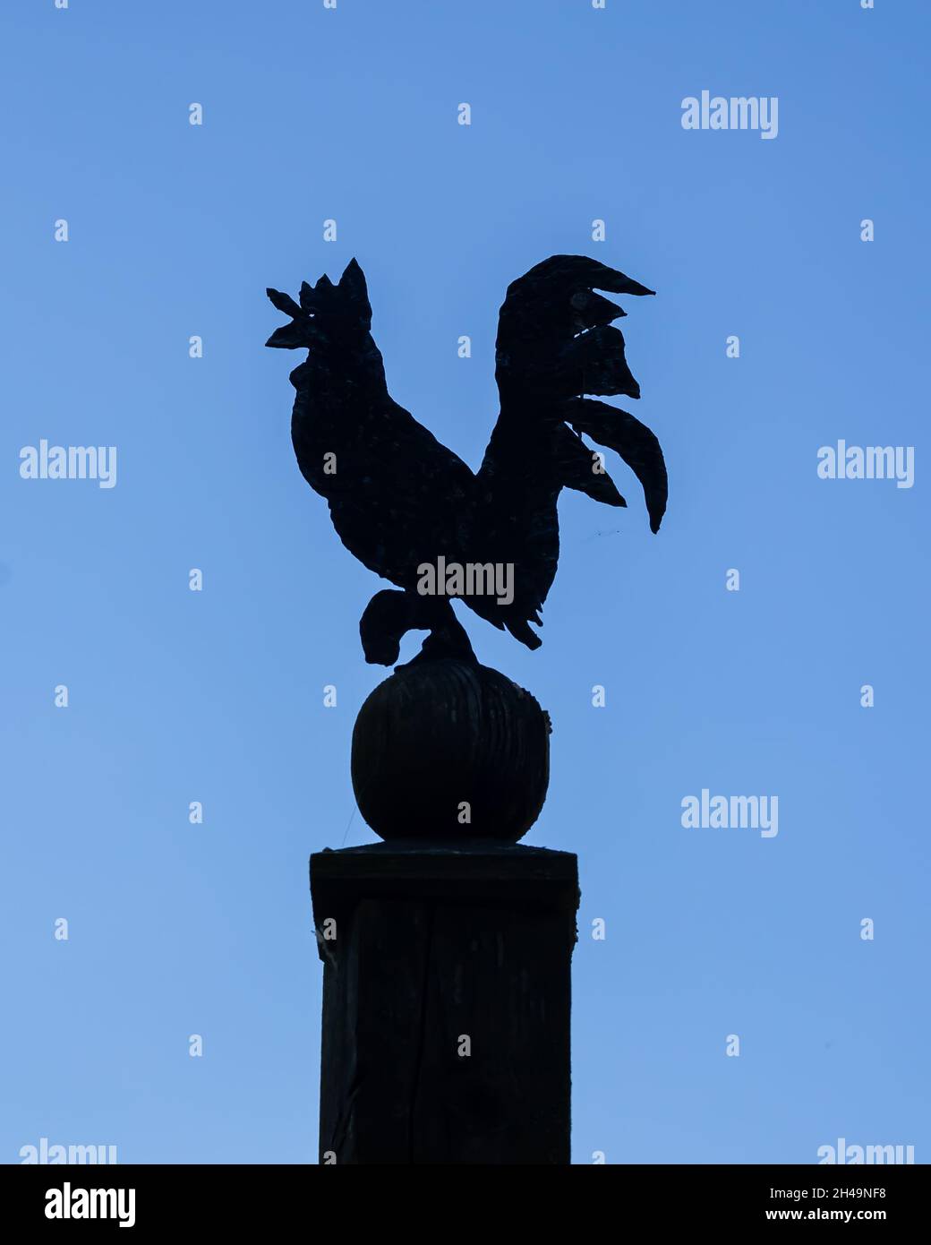 A rooster symbol, ornament made of metal, blue sky, sunny day. Open-air museum of Opole village. Stock Photo