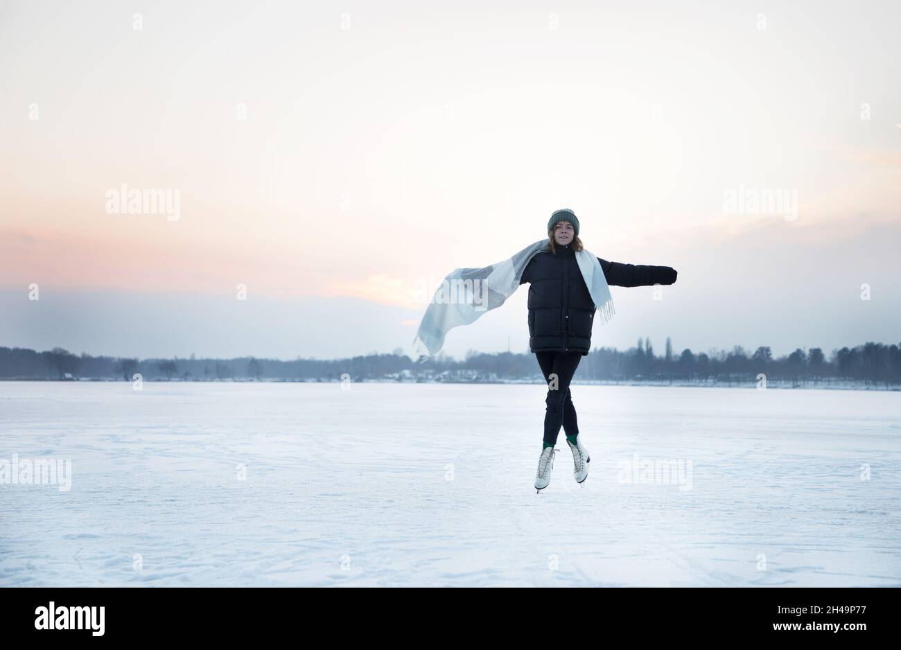 teenage girl ice skating on a frozen lake. Winter, cold weather, active sports hobby, healthy lifestyle, digital detox. Interesting winter holidays Stock Photo