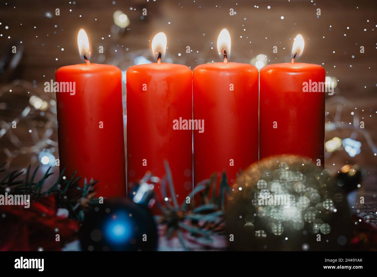 Four red advent candles with four candles lit and christmas decoration lying in snow as template