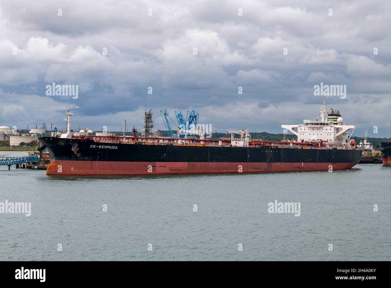 large crude oil tanker ship loading and unloading cargo at the exxon esso mobil oil refinery on the edge of the solent at the port of southampton dock Stock Photo