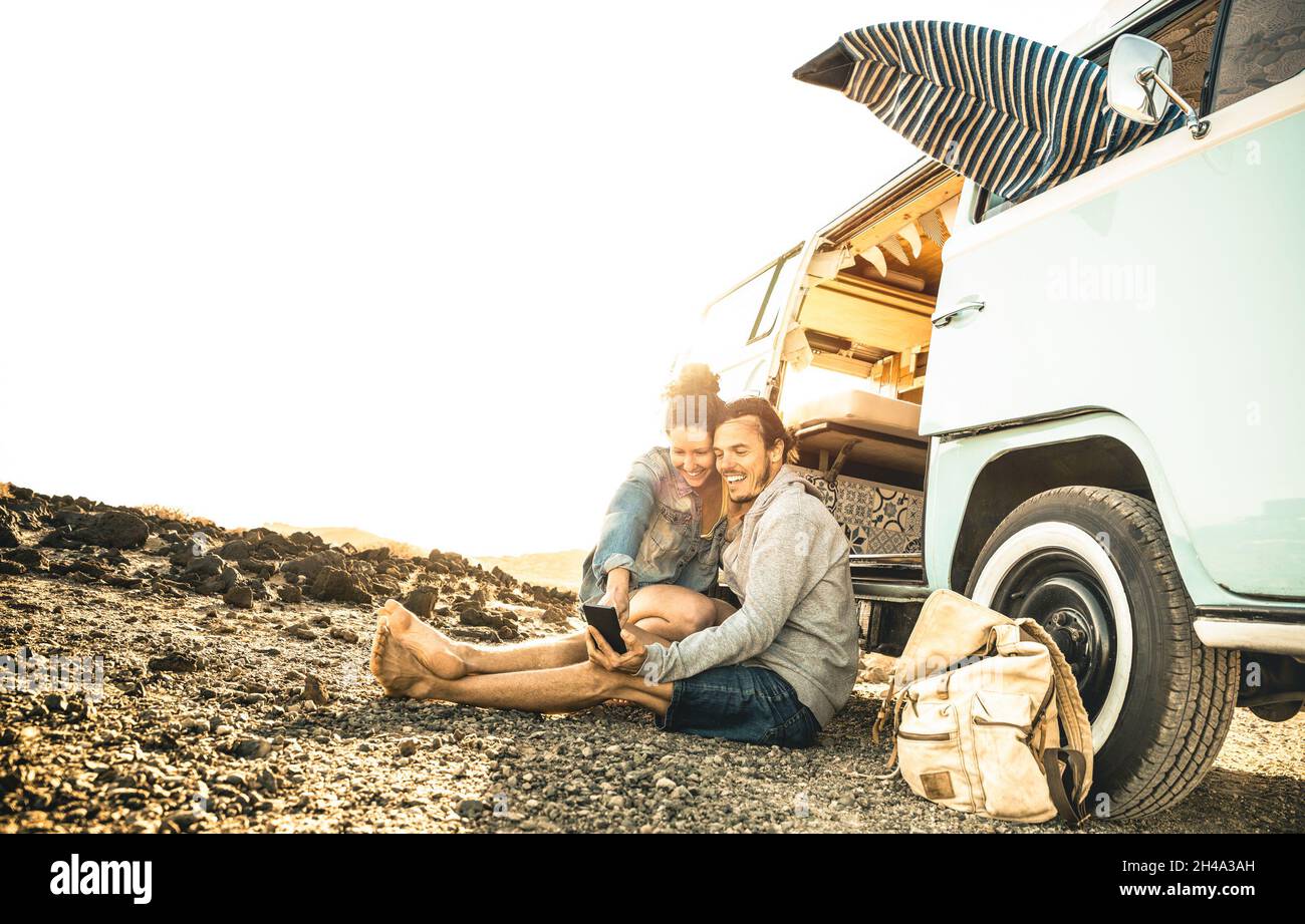 Hipster couple traveling together on oldtimer mini van transport - Travel lifestyle concept with indie people on minivan adventure trip having fun Stock Photo