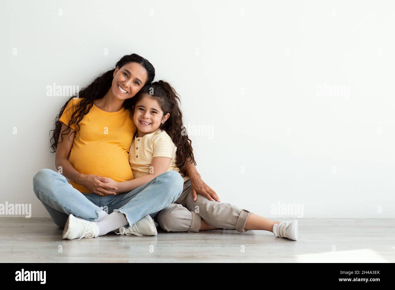 Portrait Of Happy Young Pregnant Mother And Her Little Daughter