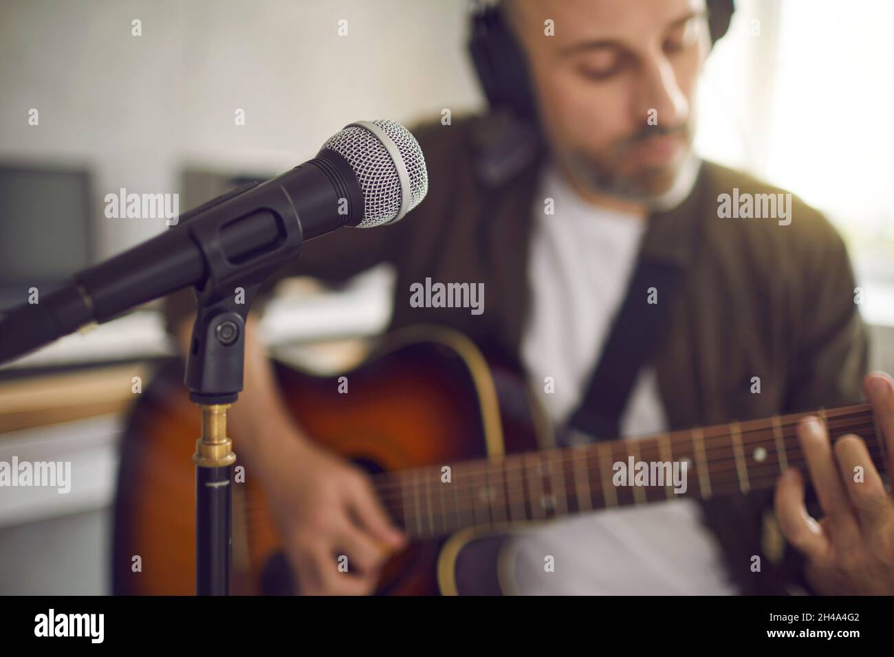 Man playing his guitar and singing into a microphone in a modern ...