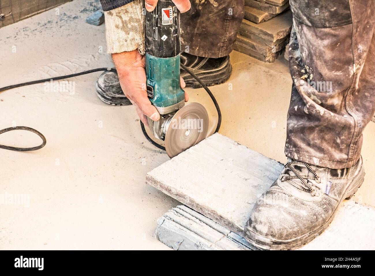 A man polishes a granite slab with a grinder. Work on stone with an angle grinder. A worker polishes a white stone. Stock Photo