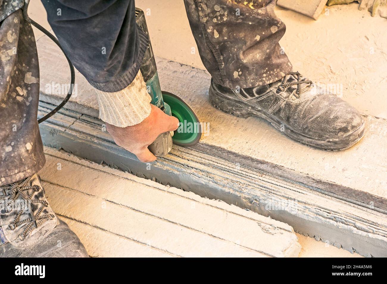 A man polishes a granite slab with a grinder. Work on stone with an angle grinder. A worker polishes a white stone. Stock Photo