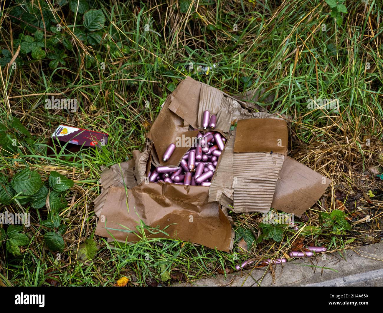 Fly-tipped Nitrous Oxide cansiters by roadside Stock Photo