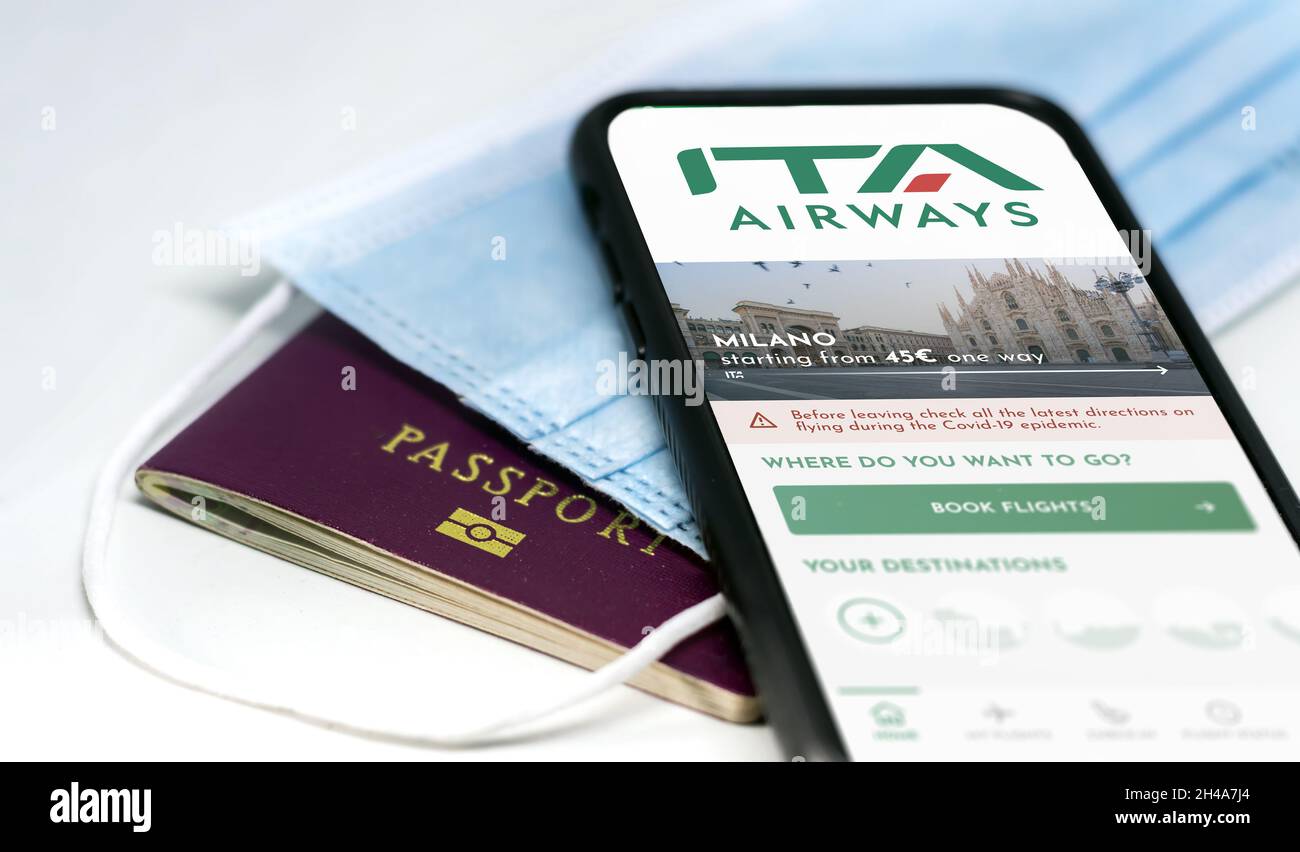 Rome, Italy, October 2021: phone with the ITA Airways app on the screen over a surgical mask and a passport. ITA Airways is the new Italian flag carri Stock Photo
