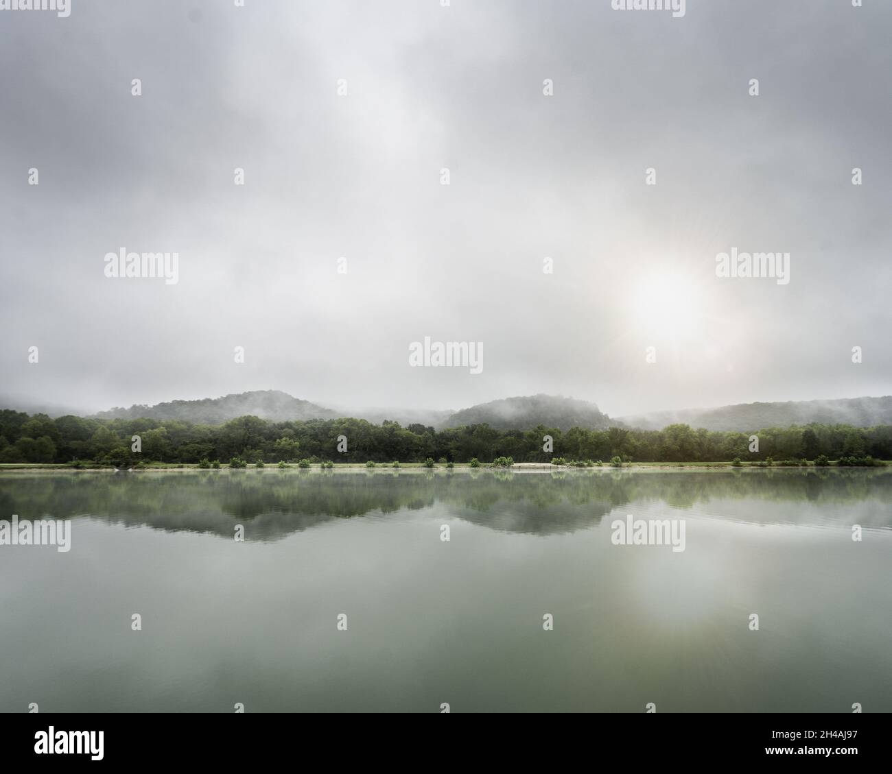Scenic view of a lake with mountains reflection on a foggy day Stock ...