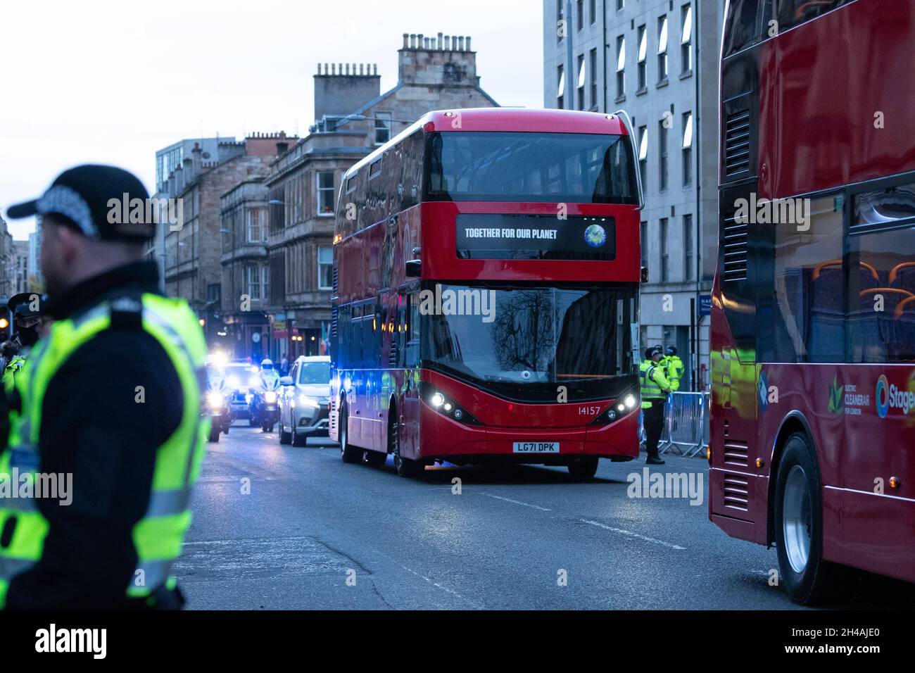 Glasgow, Scotland, UK. 1st Nov, 2021. COP26 - temporary ring of steel around Kelvingrove Museum and massive police presence in the surrounding areas of the West End of Glasgow ahead of a COP26 evening reception. Pictured - red electric London double decker buses drive along the road through Finnieston which has been completely sealed off by police to create a safe route for world leaders arriving at Kelvingrove Museum from the SEC campus. Credit: Kay Roxby/Alamy Live News Stock Photo