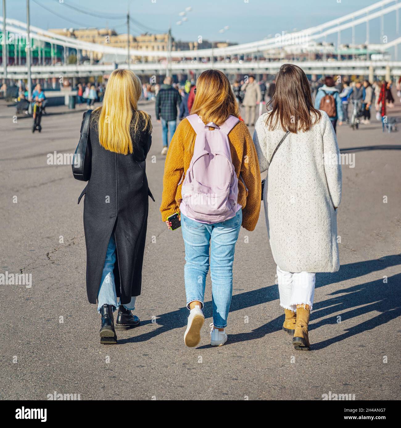 Rear view of young girls walking together in city square. Regular ...