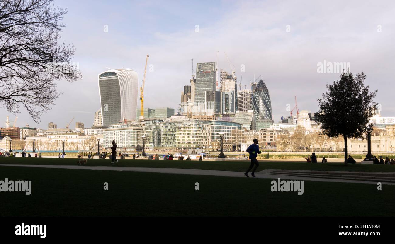 Silhouette of jogger at Potter's Fields on South Bank with City of London seen across the River Thames dominateed by modern skyscrapers. Stock Photo
