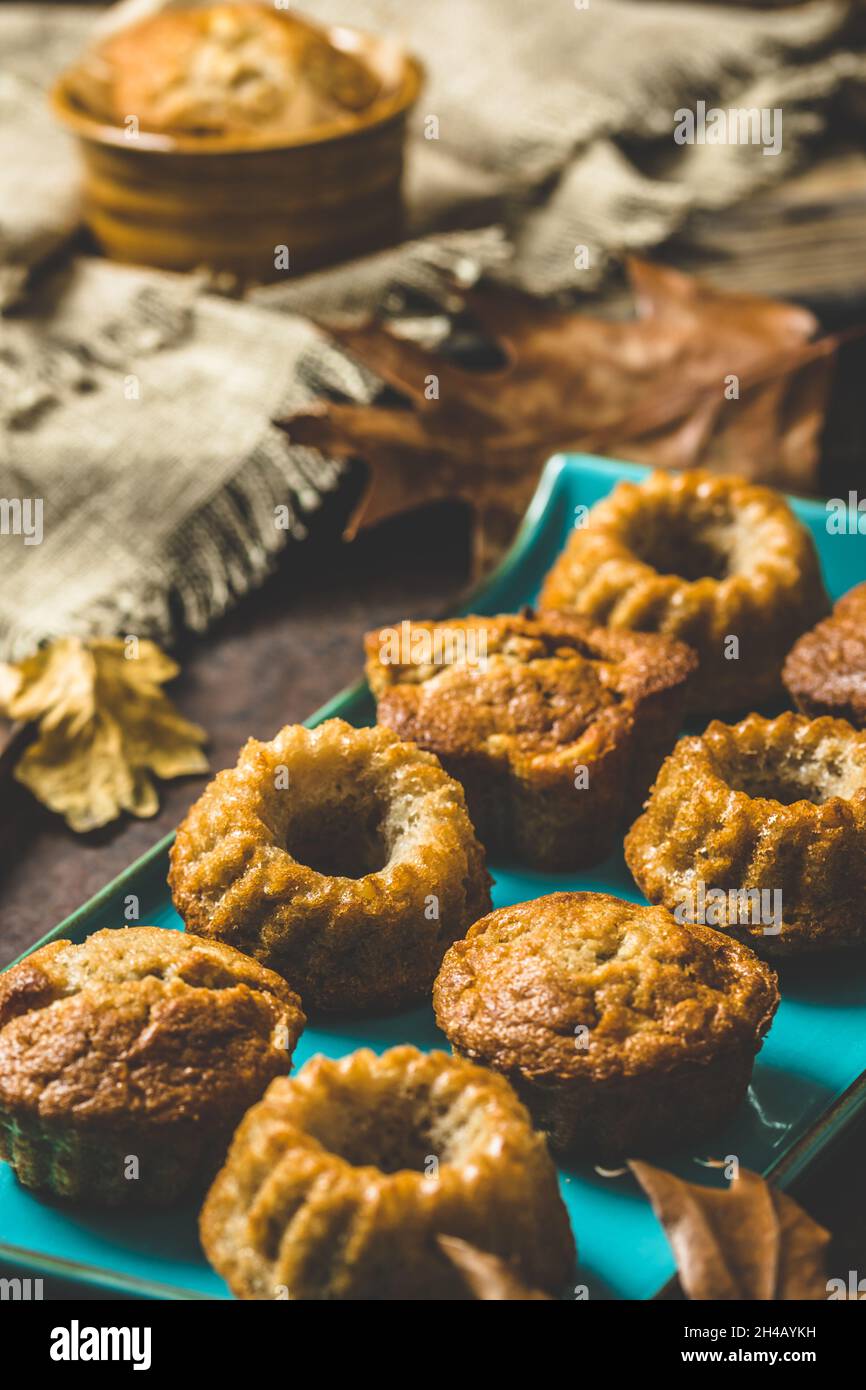 Homemade delicious mini bundt cakes, guglhupf, muffins on a blue plate on rustic wooden background with autumn decoration, vertical Stock Photo