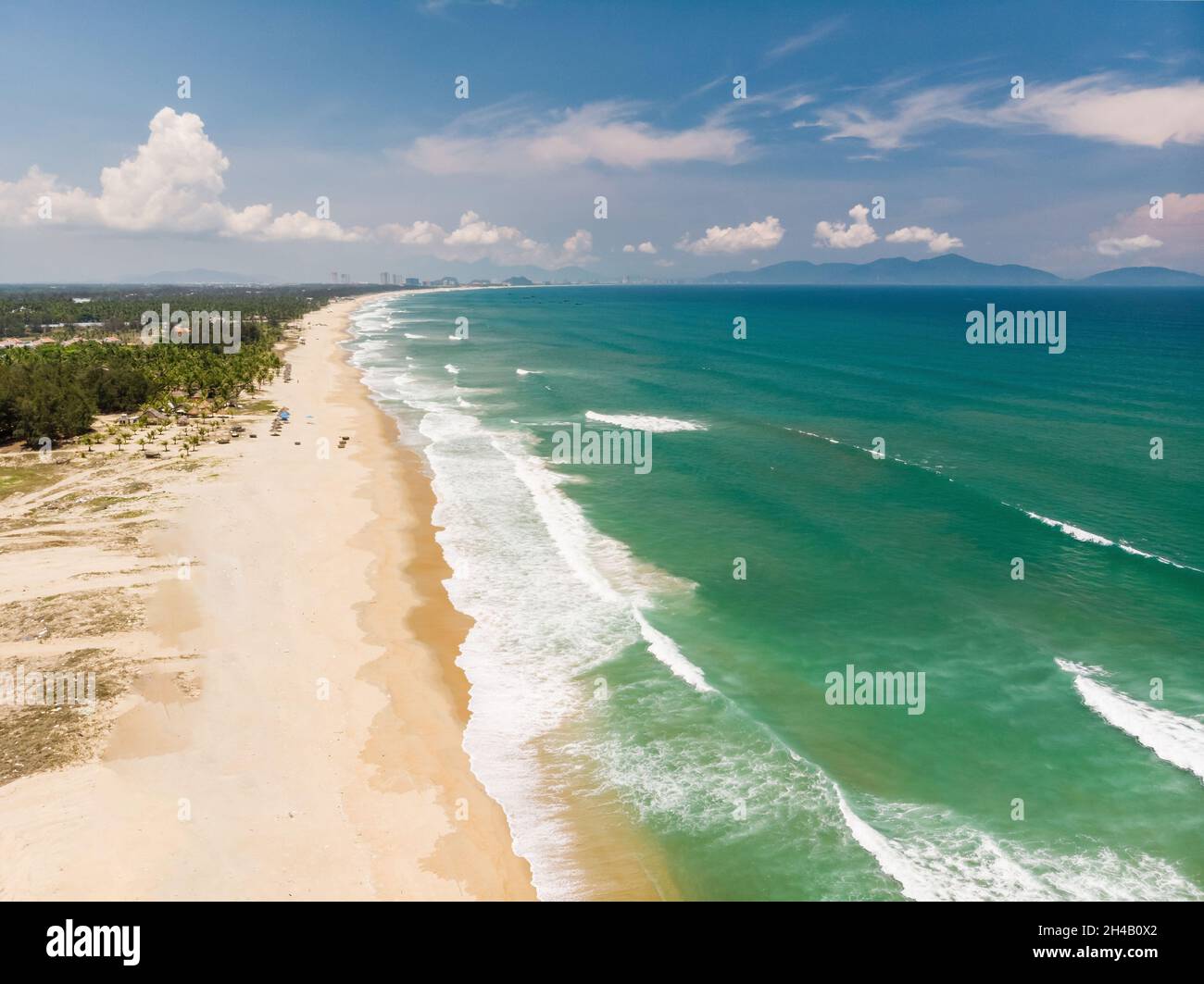 Aerial view of beautiful vietnamese landscape, beach by emerald South China Sea near Hoi An under blue cloudy sky, and distant city Da Nang, Vietnam Stock Photo