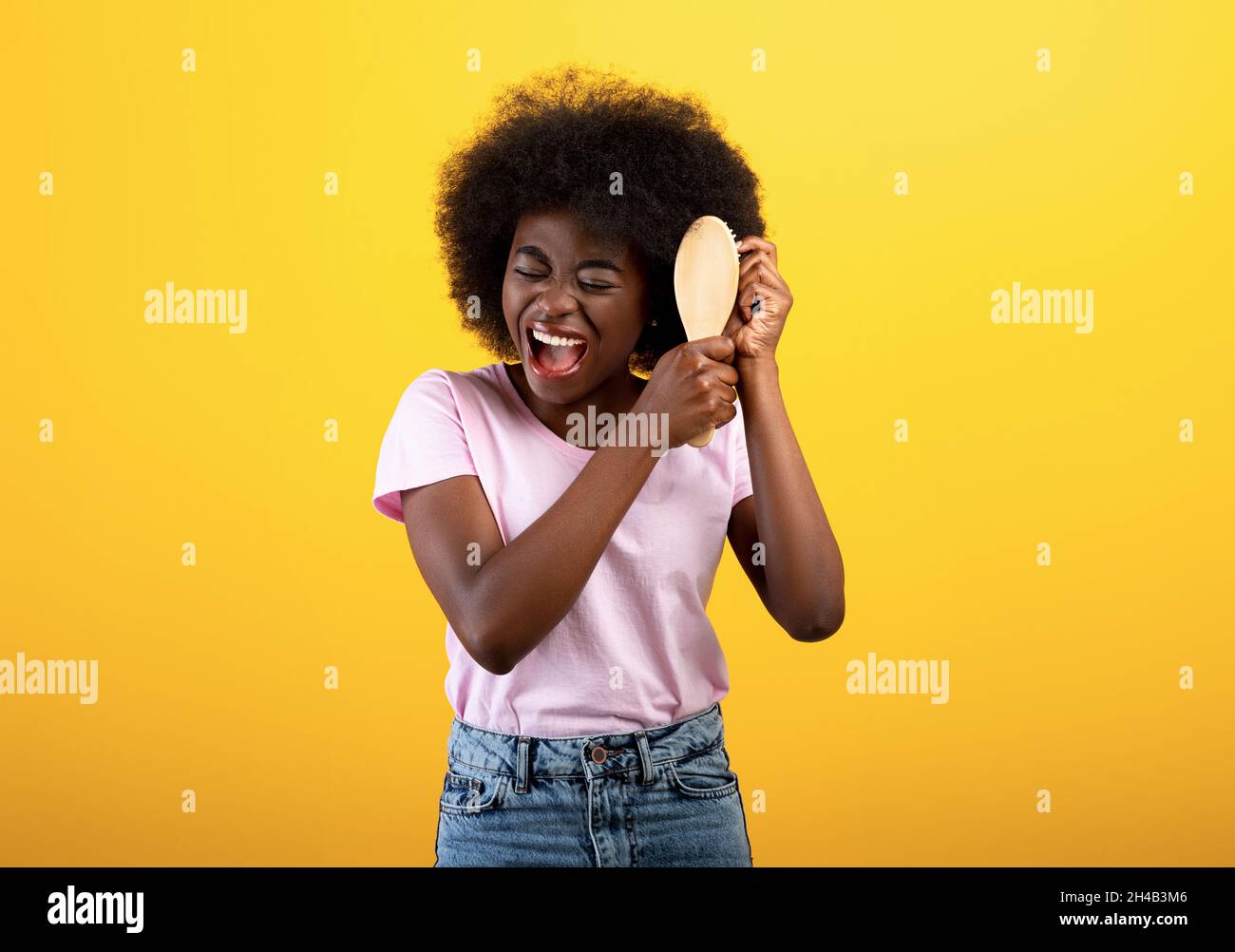 Hair detangling. African american lady brushing bushy tangled hair with