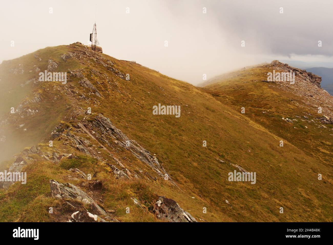 A view looking across the peaks of Ben Stack, Sutherland, Scotland with the omnidirectional radio antenna in view and mountain mist arriving Stock Photo