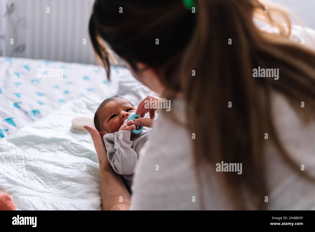 Mother putting pacifier to her baby in bed Stock Photo Alamy