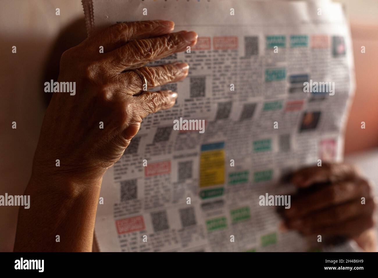 Wrinkled hands of senior female reading a newspaper, Cartagena de Indias, Colombia. Stock Photo