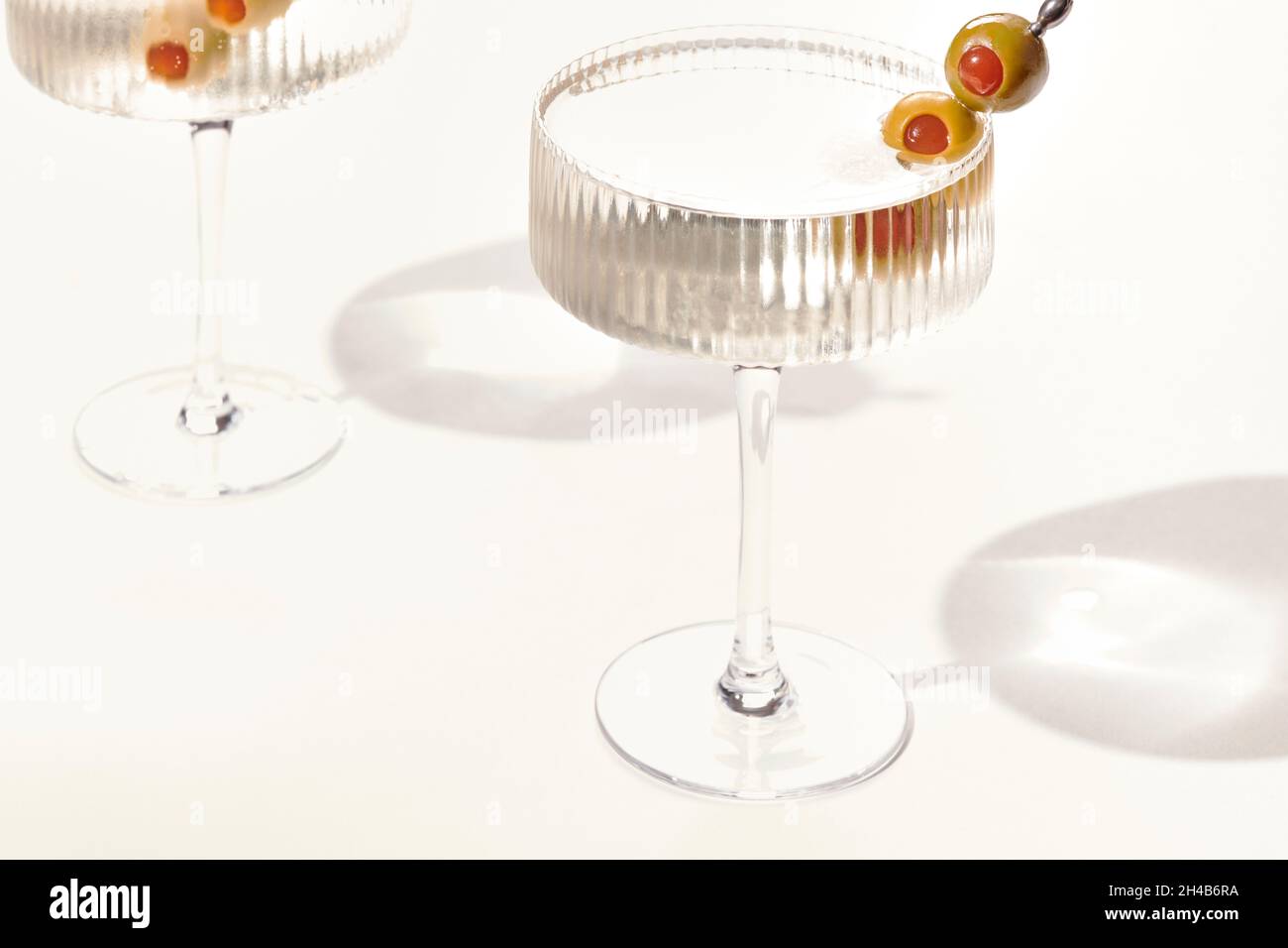 Two cold vodka or gin martini with olives garnish on white background