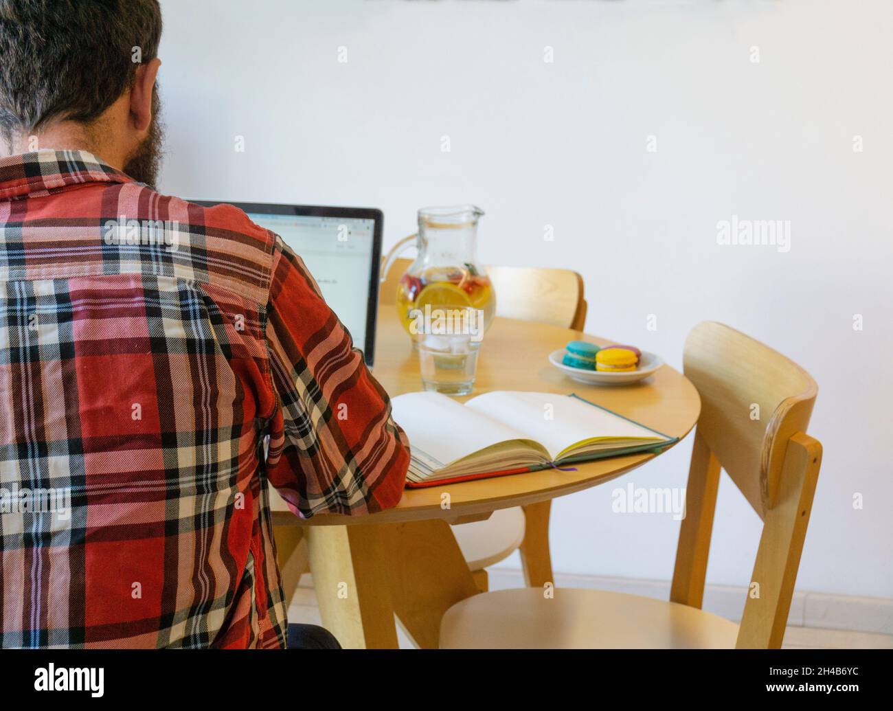 Rear view of man working on his laptop in the table with food Stock Photo