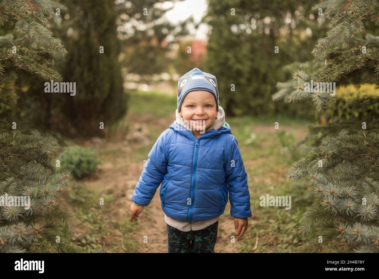 Small boy in blue clothes in garden smiling Stock Photo
