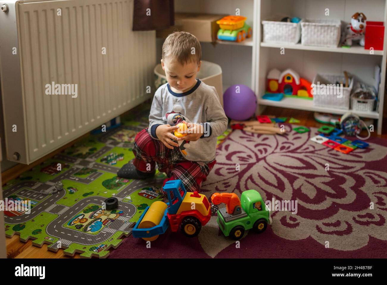 Small blonde boy in his room sitting on the floor and playing wi Stock ...