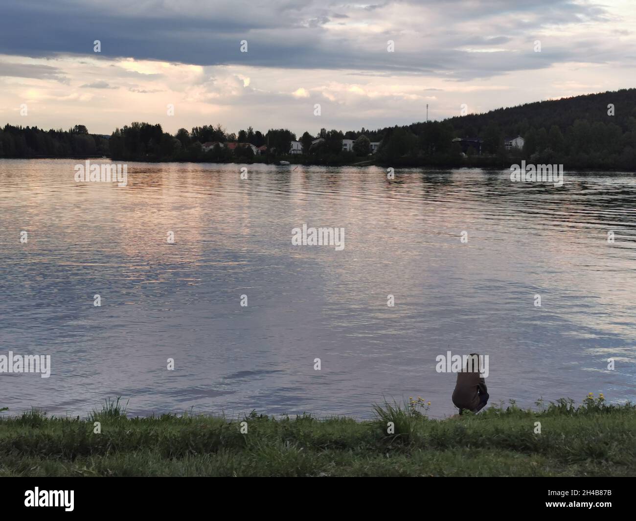 A worried man sitting in front of a lake. Mirroring from water. Stock Photo