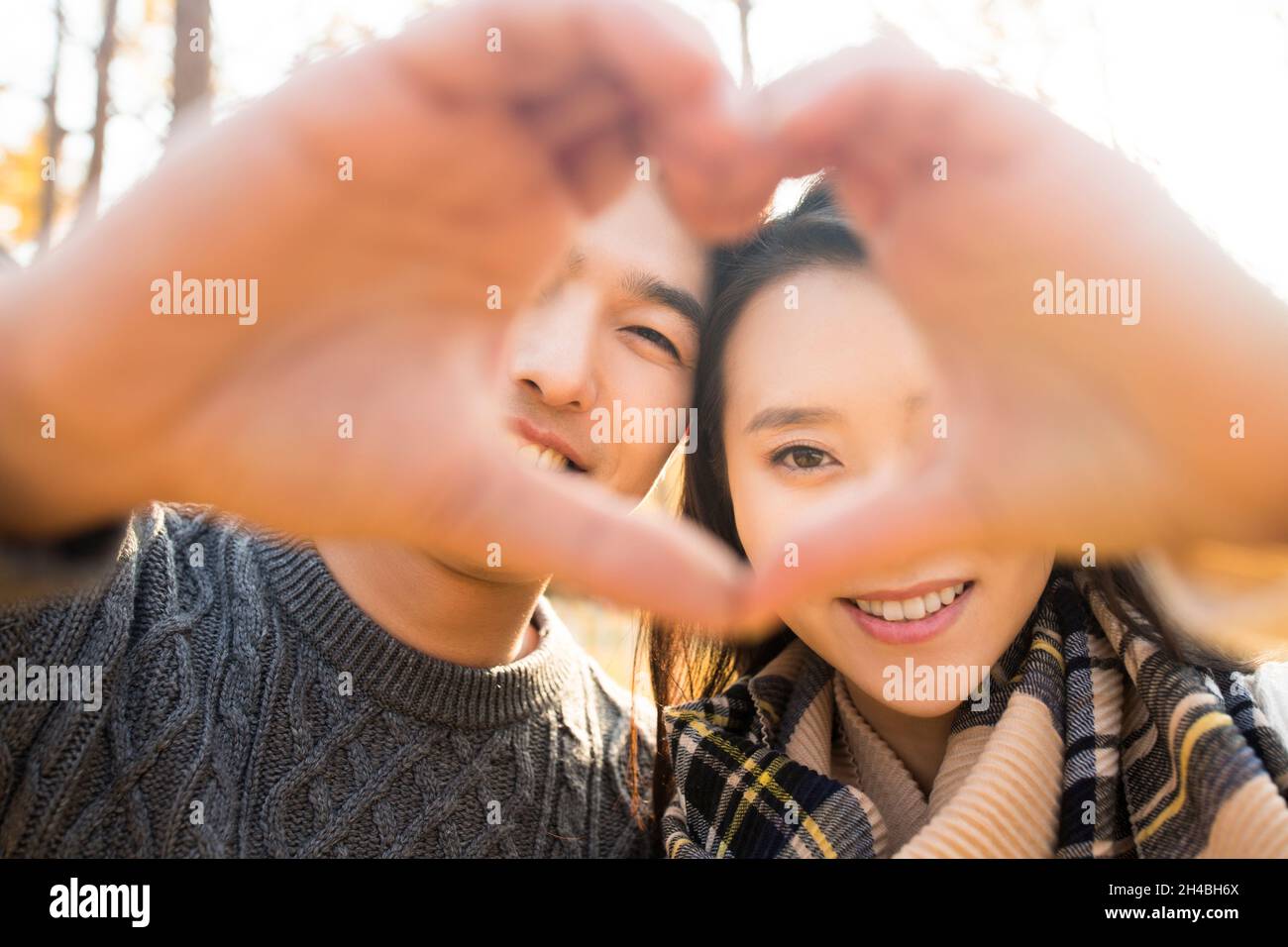 Happy young lovers making heart gesture Stock Photo