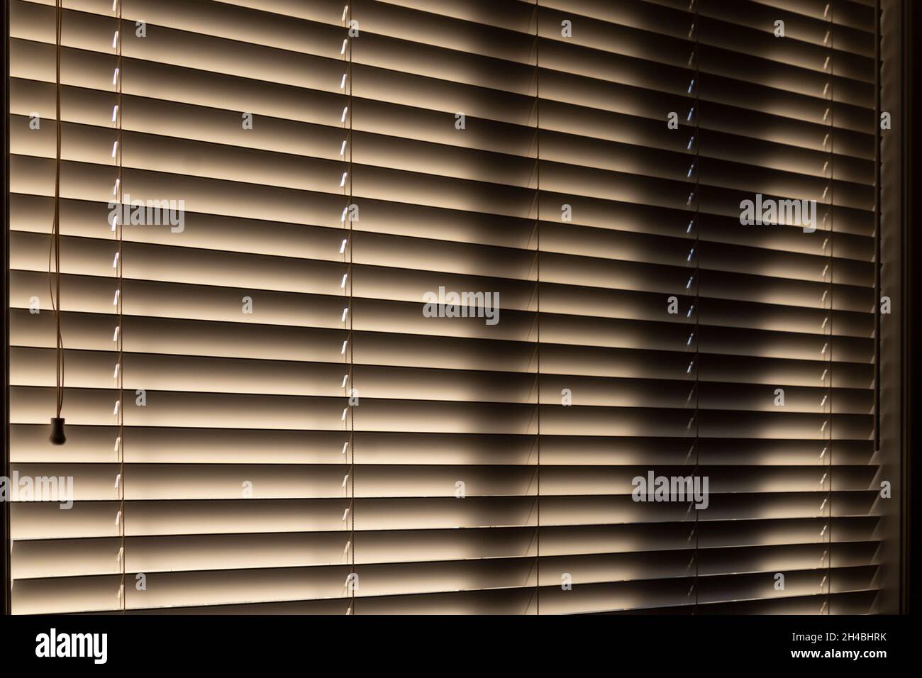 Office blinds, dark inside with sun peaking through from outdoors Stock Photo